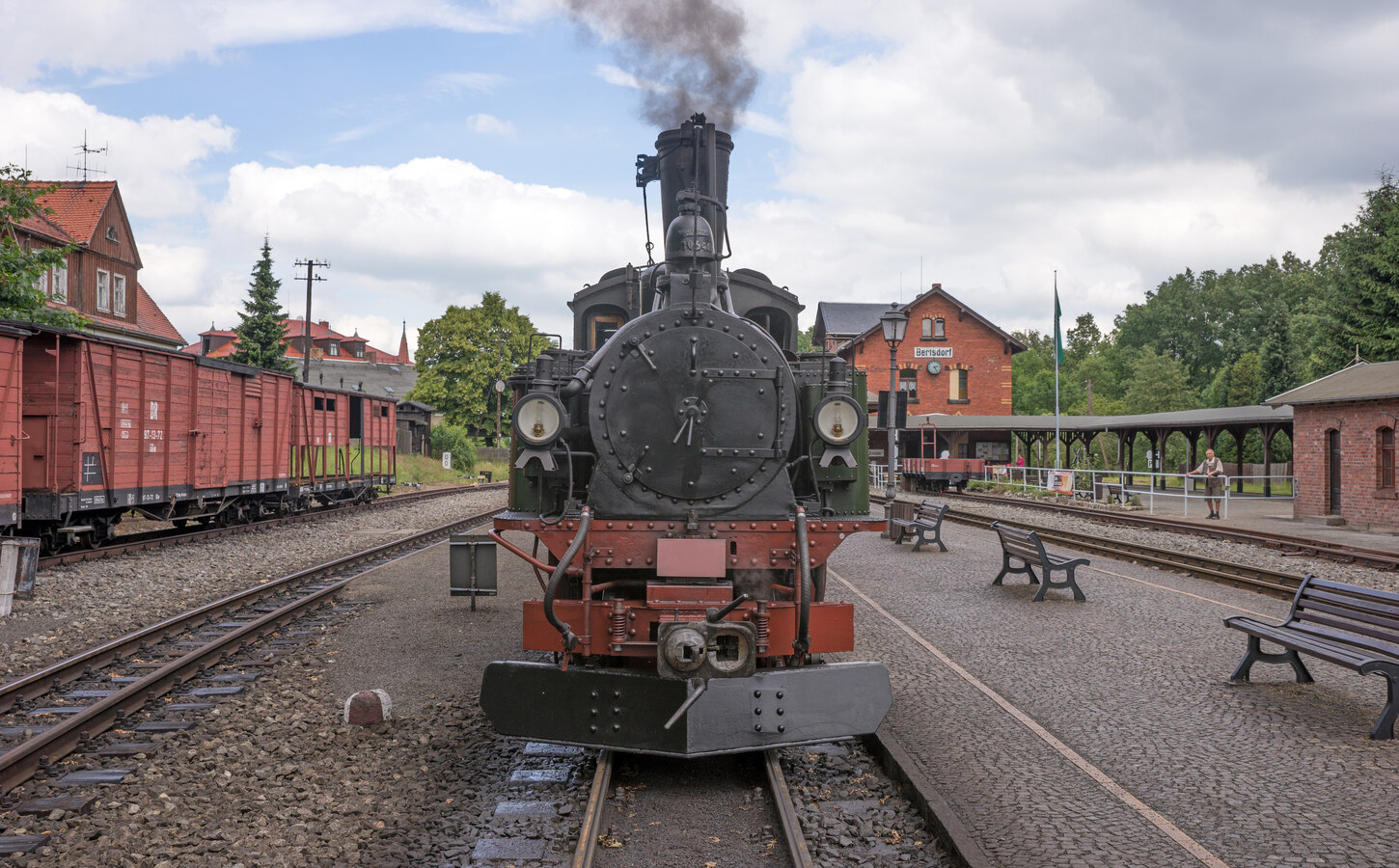 Eine Schmalspurlok steht dampfend im Bahnhof.