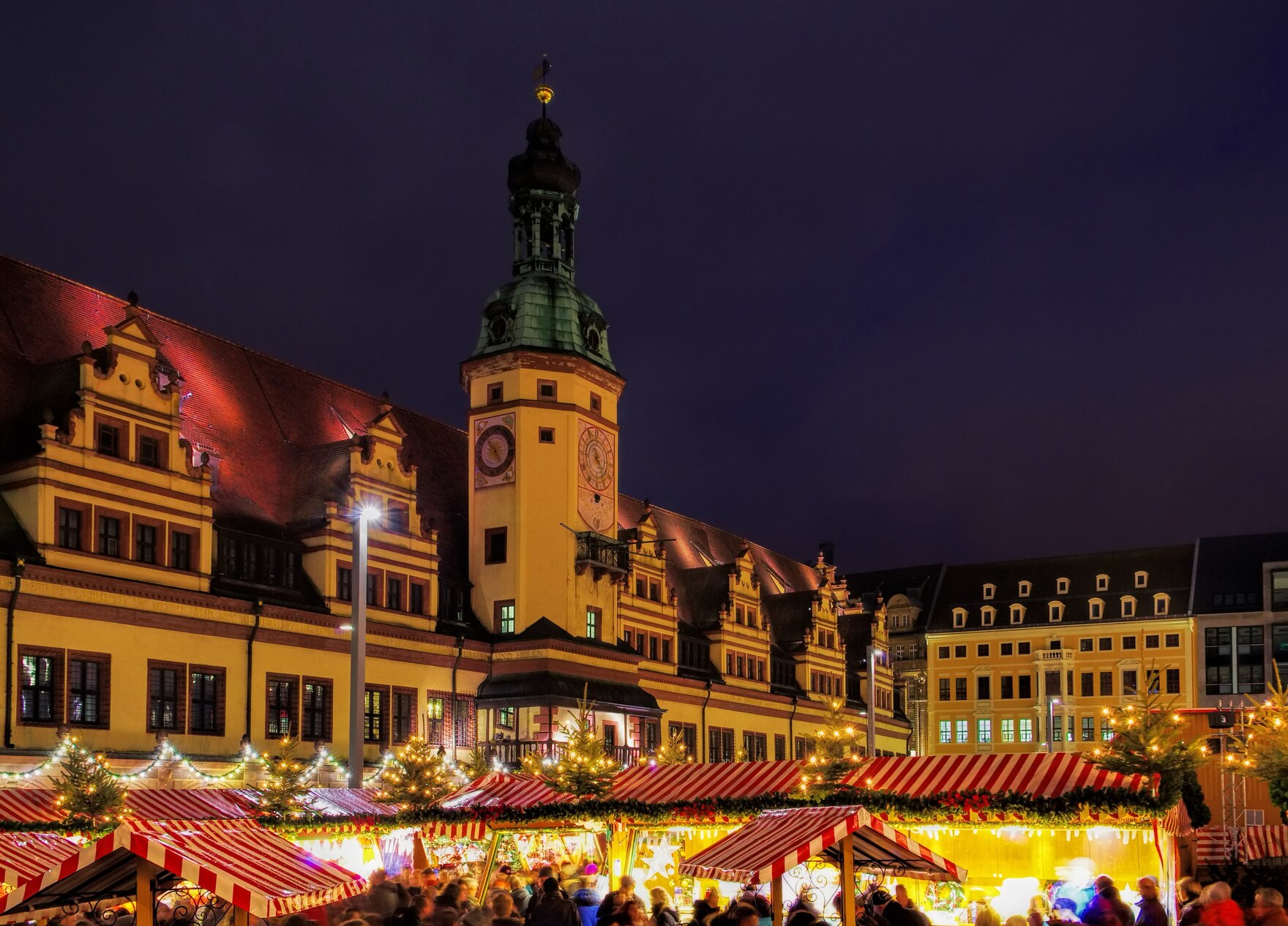 Blick über die erleuchteten Buden des Leipziger Weihnachtsmarktes. Im Hintergrund ist das Rathaus zu sehen.