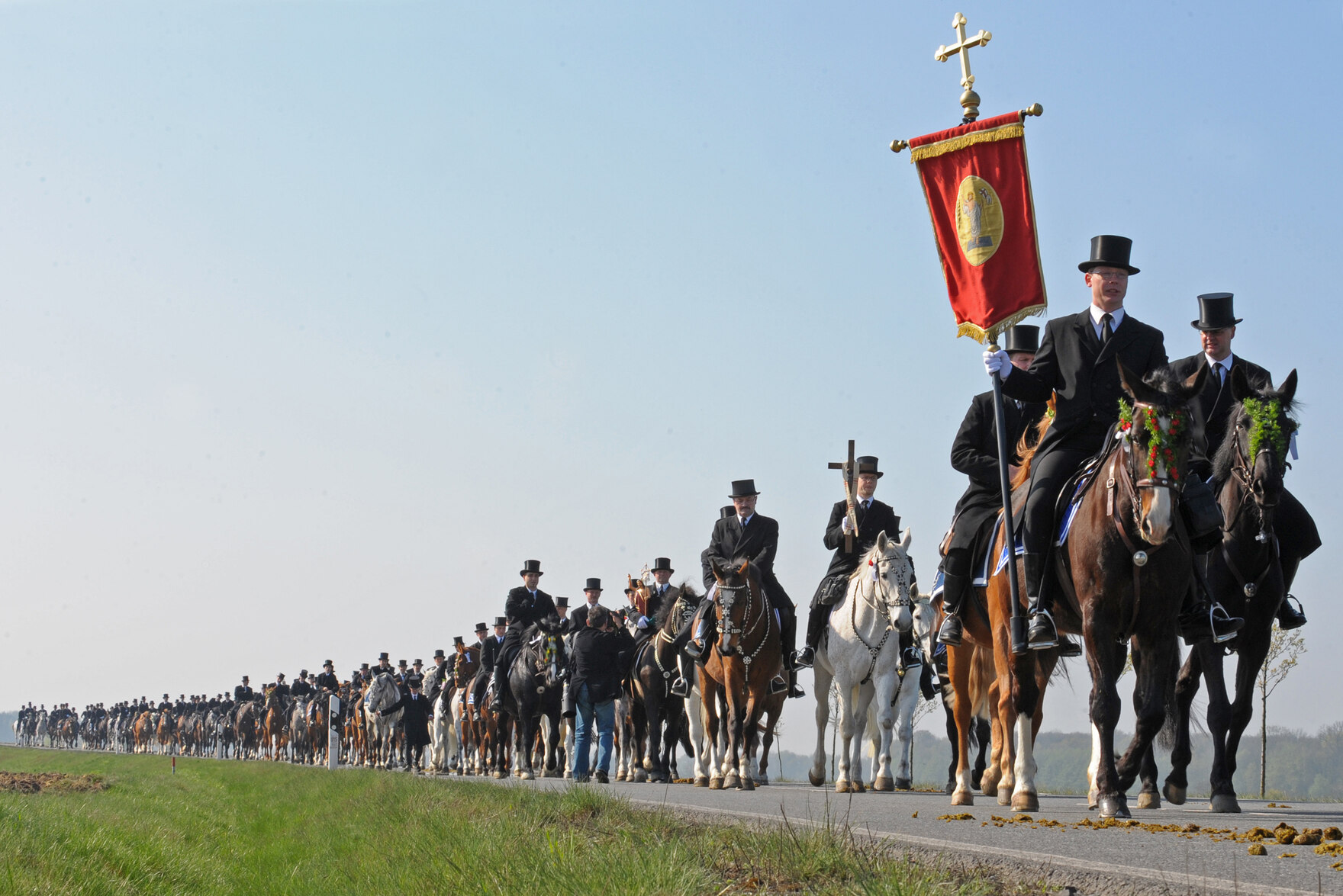 Viele Männer reiten auf Pferden über eine Straße. 