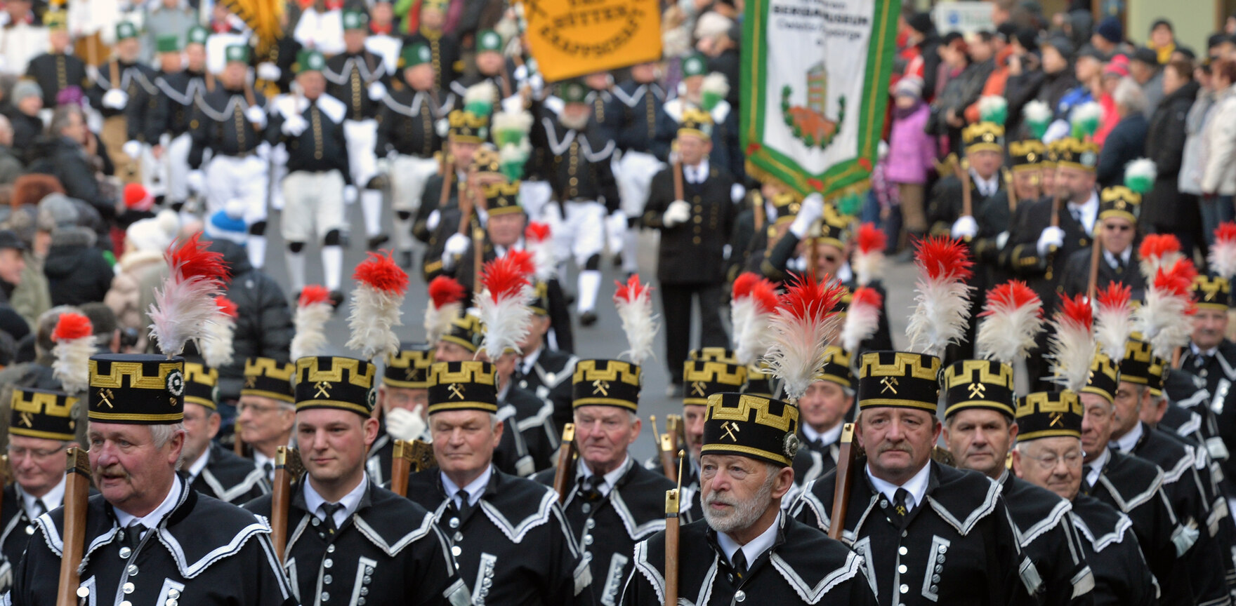 Festlich gekleidete Trachtenträger des Bergmannszuges marschieren durch die Straßen.